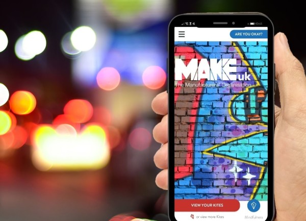A person holding a phone displaying the Make UK branded Kite app